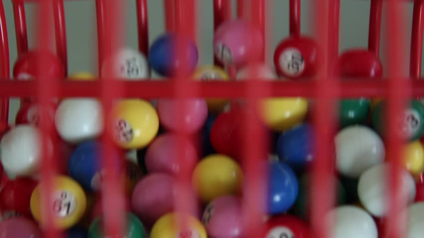 Colorful bingo balls tumbling in bingo machine from the front.