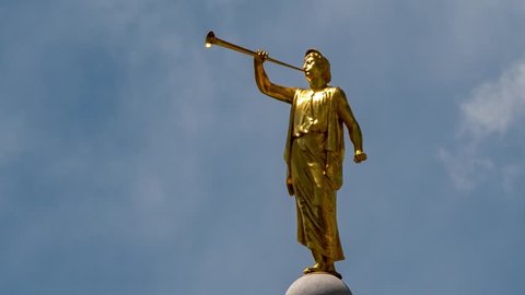 Time lapse cloudscape of Angel Moroni - the Mormon prophet shown as a golden statue on the top of Mormon Temples. Zooming out to reveal a wider scene.