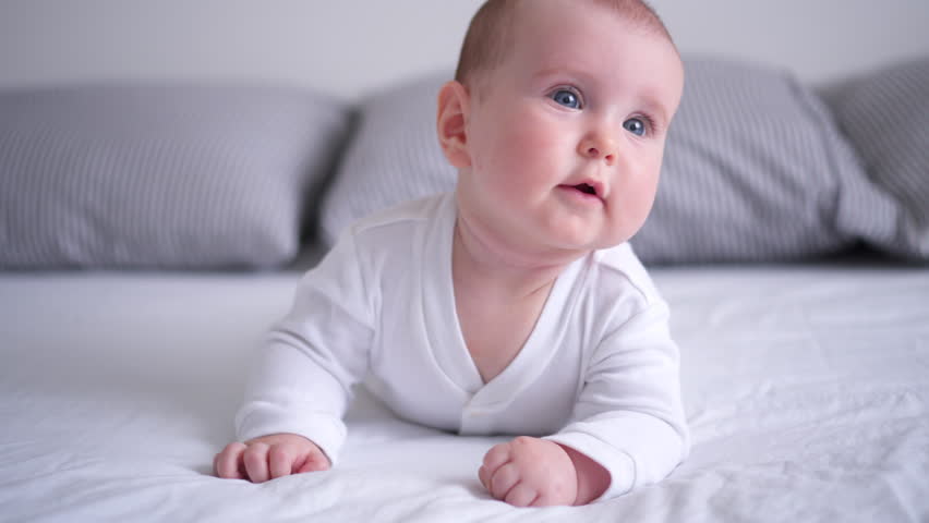 Curious baby girl lying on stomach and looking aside | Shutterstock HD Video #1011312770