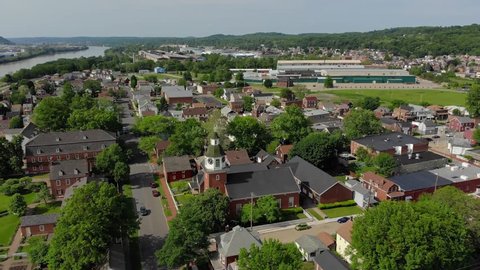 A forward aerial establishing shot of a Pennsylvania small town's business and residential districts. Ohio River in the distance. Pittsburgh suburbs.  	