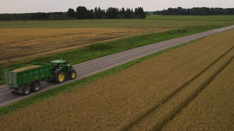 Aerial Shot of a Tractor with Trailer Moving on the Rural Road. Rural Area with Fields on both Sides. Shot on 4K UHD Camera.