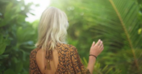 Following Back View Shot of a Beautiful Young Blonde Woman Wearing a Dress Walking Through Lush Green Forest on the Exotic Tropical Islands. Shot on RED Epic 4K UHD Camera.: stockvideo