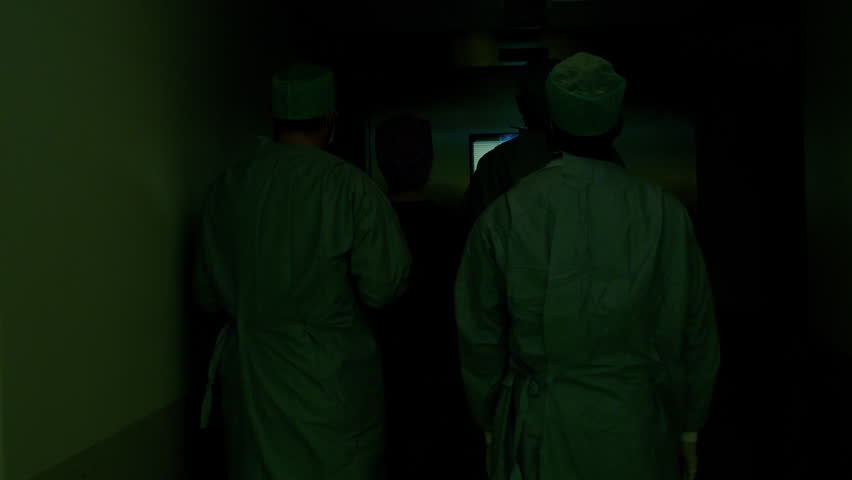 Following Shot of Diverse Team of Surgeons and Assistants Walk into Operating Room Where Patient Waits, they put Him under Anesthesia and Start Surgery. Shot on RED EPIC-W 8K Helium Cinema Camera.