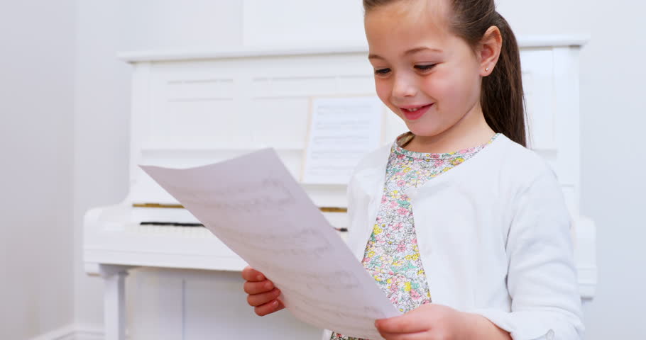 Smiling cute girl holding sheet music at home 4k