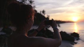 The girl is taking pictures of a beautiful golden sunset on the phone. slow motion, 1920x1080, full hd