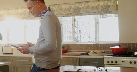 Man using mobile phone while having coffee in kitchen at home 4k