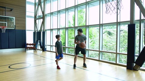 Young man teaching boy how to play basketball