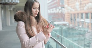 emotions, technology and people concept - smiling young woman or teenage girl texting smartphone. Woman walking in street talking a voice message on smartphone. talking on the phone. writes a message