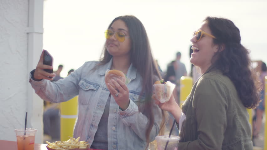 Excited Young Women Pose With Their Burgers For Fun Vacation Selfies On The Santa Monica Pier (Shot On Red Scarlet-W Dragon In 4K, Slow Motion) Royalty-Free Stock Footage #1011346895