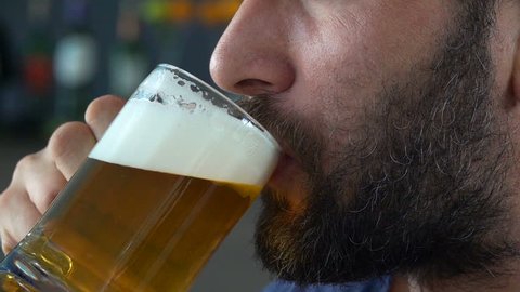 Close up of male face drinking beer in cafe, super slow motion 240fps
