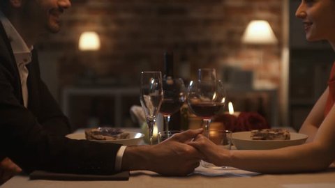 Romantic happy loving couple having a dinner date, they are holding hands and talking, feelings and relationships concept