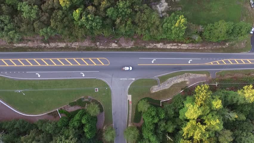 Aerial tilt up shot of a highway cutting through a forest at sunset.