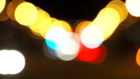 Bright circles from streetlamps on defocused video of night street. Urban abstract texture ,bokeh of city lights in the background with blurring lights for your design. Cars and walking people.