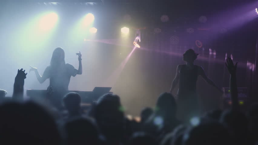 Two beautiful young women DJ play the music on the mixing console in the nightclub. Against the background of unrecognizable people. Slow motion Royalty-Free Stock Footage #1011370961