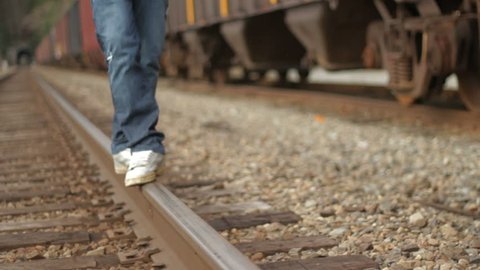 A man balances on a train rail.