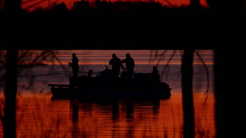 Silhouette of family in pontoon, fishing on Lake Irving at sunset in Bemidji, Minnesota.