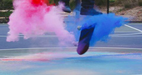 Skateboarder does extreme flip trick with colored powder in slow motion 