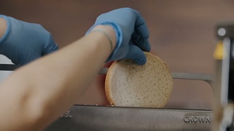 Fresh toast bread put by cook in into toaster for hamburger or cheesburger buns. Cooking in fast food restaurants for junk fat food. Fresh baked toast bread for breakfast, cooking process in kitchen