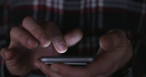 Online gambling: a close up of a man placing a bet via online gambling on his phone late at night and crossing his fingers for good luck. 4k Slow motion.