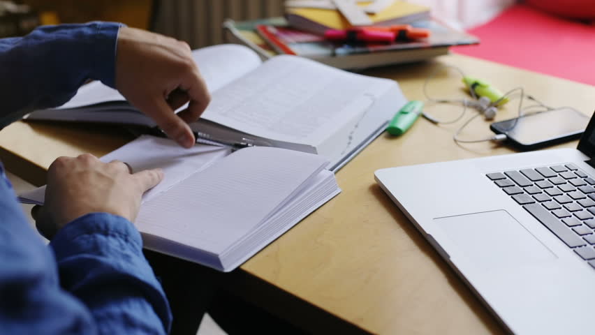 close-up view of young man writing information notes in copybook then typing text on laptop keyboard studing brainstorming preparing exam 