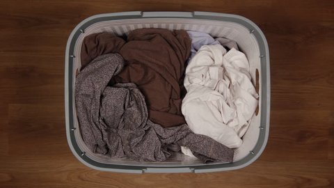 TOP VIEW: Dirty clothes are filling a laundry basket on a floor - Stop Motion