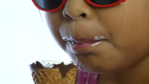 Close-up Asian a little girl licking ice cream in a cone during summertime