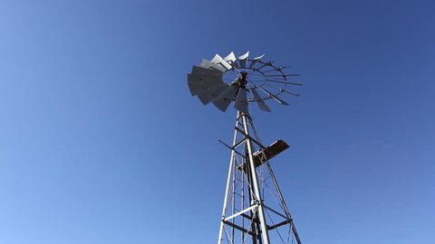 Hero shot looking up at a windmill windpump spinning against blue skies in Karoo South Africa