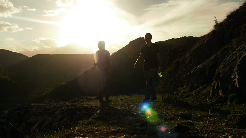 Silhouette People hikers hiking in mountains. Hiking couple walking on trail. Healthy lifestyle hiker people walking in mountains. Young woman and man hikers on path. Travel  wanderlust concept. 