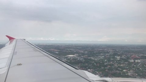Bangkok, Thailand - May 22,2018 : Air Asia plane flight. Wing of an airplane flying above the clouds look at city Chiangmai. View from the window of the plane. Aircraft.
