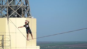 A man balances on a tight rope, extreme highline