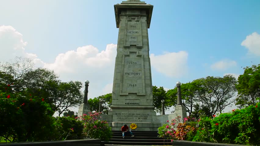A view of victory war memorial on world war 1 and world war 2 at Chennai. Happy smiling young man sitting and text message on smart phone