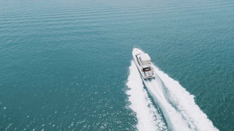 Large white yacht at speed in the Emirates. 4K cinematic video from drone