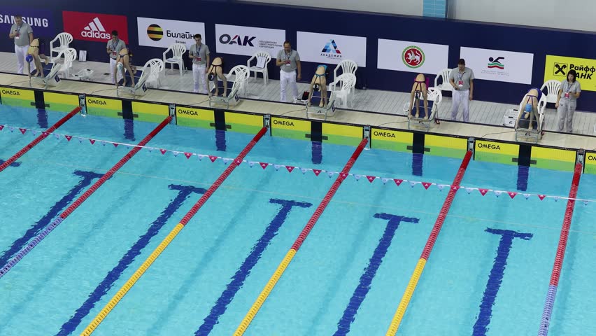 KAZAN, RUSSIA - DEC 09, 2017: Women jump to water and start swimming race under arbiters observation in Burevestnik basin during All Russia Swimming Competition, Alexander Popov Cup