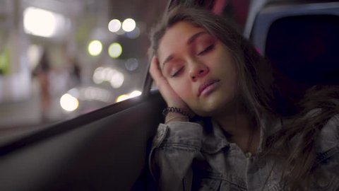 Portrait Of Young Woman Sleeping In Back Seat Of Moving Car, In City (Slow Motion)