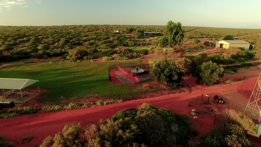 An aerial wide shot of a forest and house with sky. Camera moves backward