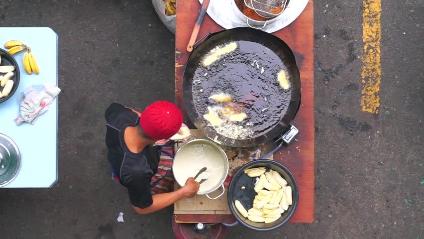 Food vendor cooking popular Malaysian fried banana.Oily food made from banana mix with white flour and serve with kitchup source and known as "goreng pisang". Footage Royalty-Free Stock Footage #1011453386