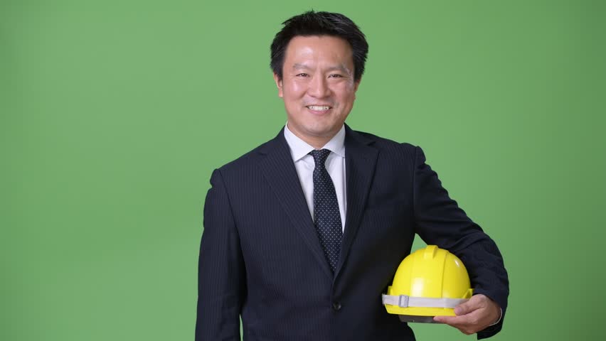 Mature Japanese businessman against green background