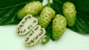 Top view fresh noni fruit in leaf on white background and poring water clips