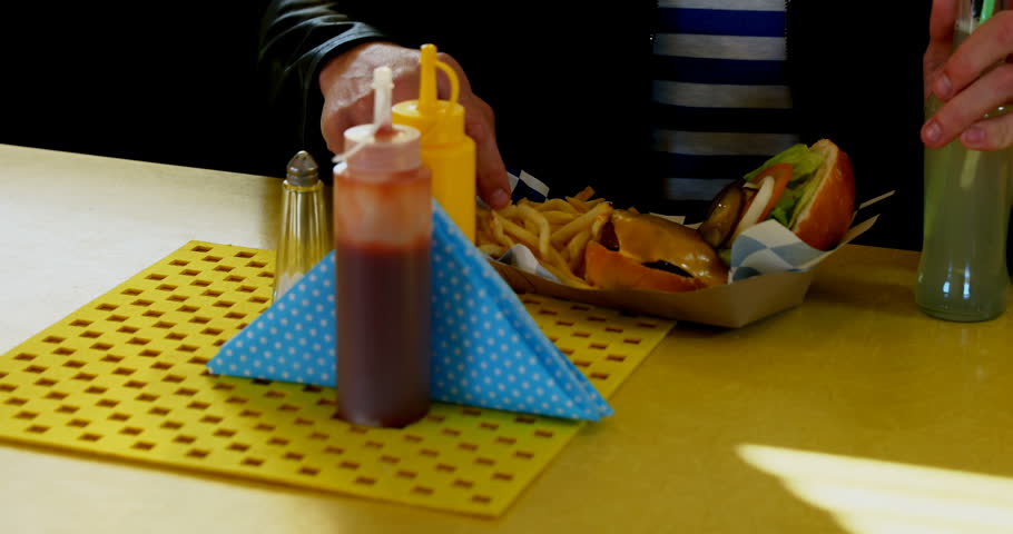 Man drinking juice while having french fries in cafe 4k