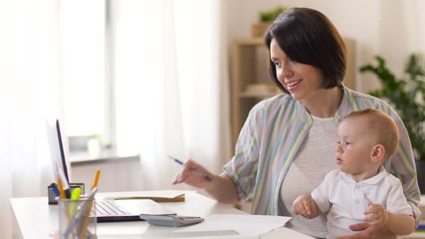 multi-tasking, freelance and motherhood concept - working mother giving pen to baby boy at home office