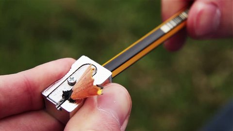 Man sharpening a Pencil with Sharpener Outdoors. Close-up.  