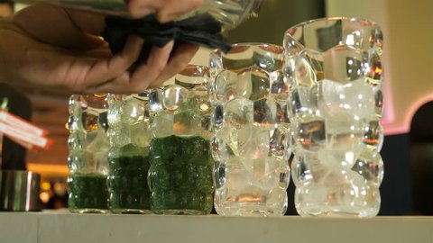 Preparation of a cocktail in five glasses based on greenery, the barman pours a cooked cocktail in the shaker, soft cocktails, a barmaid, bartender competition, a healthy lifestyle, a healthy diet, a