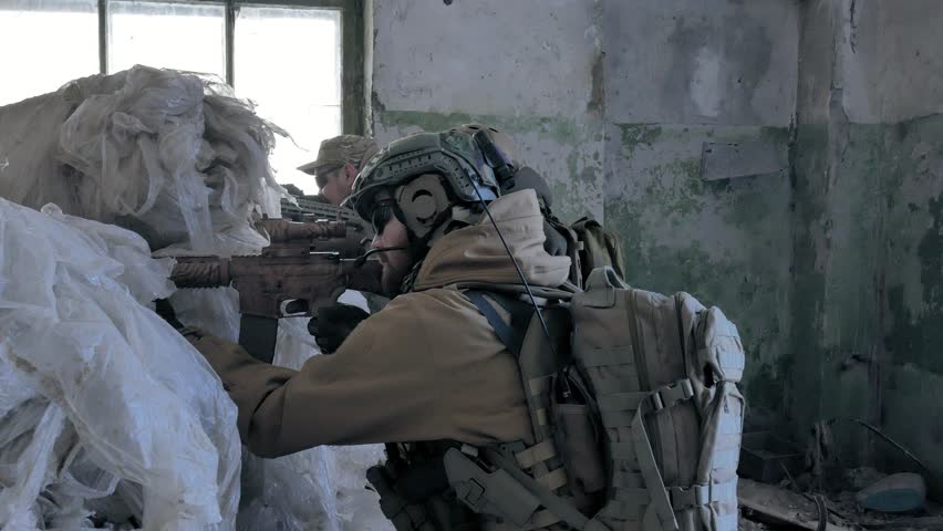 Soldiers in camouflage with combat weapons are being fired in the shelter of the old building, the military concept 4k