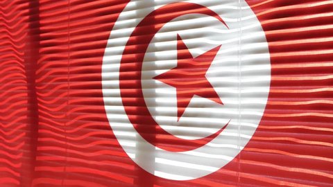 Tunisian flag hanging at wide jalousie window. Closeup 