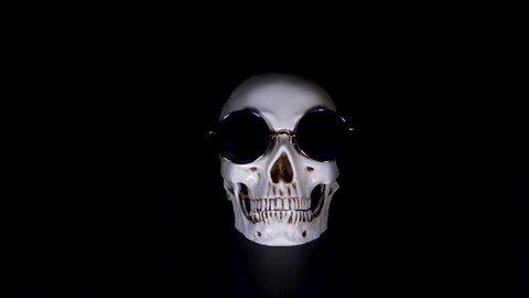 Skull in round sunglasses on a black background. close-up. 4k, dolly shot, defocusing, blur.