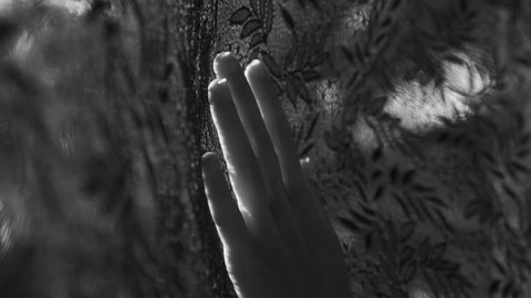 Closeup woman's hand touching black lace curtain - black and white video in slow motion