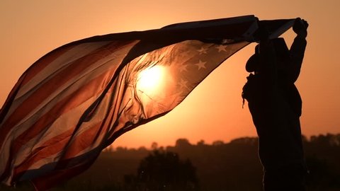 Slow Motion Footage of Caucasian American Cowboy Patriot Running with Flag During 4th of July Independence Day Sunset.