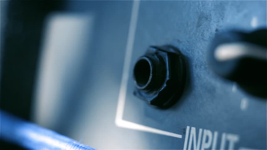 Male Hand plugging Jack Cable into Guitar Amplifier. Blue Tone. Close-Up. Royalty-Free Stock Footage #1011503261