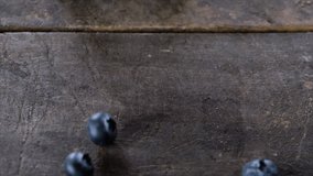Blueberries rolling on a wooden board. Slow motion.