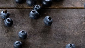 Blueberries rolling on a wooden board. Slow motion.